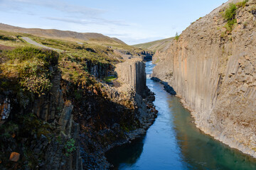 Explore the breathtaking Studlagil Canyon in Iceland, where towering basalt columns meet a serene river.
