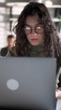 Young Business Woman Professional Entrepreneur Using Laptop Computer Notebook At Workplace Typing Email Making Notes Sitting At Desk Working Doing Online Job In Modern Office. Vertical Video