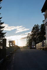 Urban street under repair at sunset with traffic warning signs, fences and trees on both sides.