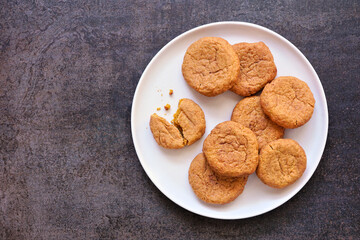 Plate of autumn pumpkin spice snickerdoodles. Overhead view with a dark stone background.