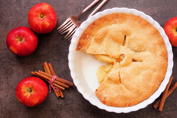 Autumn apple pie. Top down view table scene with slice removed on dark background.