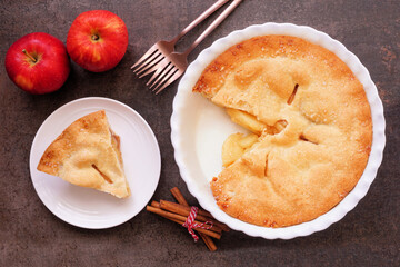 Fall apple pie. Above view table scene with cut slice on dark background.