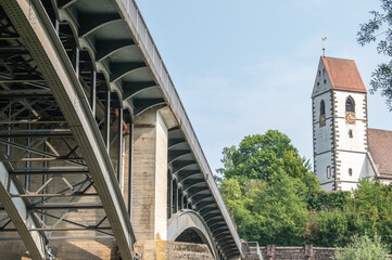 Neckarbrücke in Plochingen mit Betonpfeilern und Stahlbögen vor Stadtkirche St. Blasius unscharf...