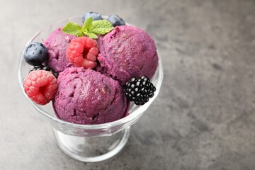 Delicious sorbet with fresh berries and mint in dessert bowl on grey textured table, closeup. Space for text