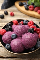 Delicious sorbet with fresh berries in bowl on wooden table, closeup