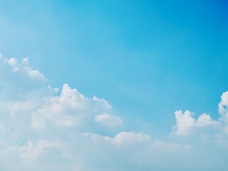 Bright blue sky with fluffy white clouds in natural daylight background.