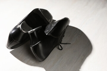 Pair of shoes for tap dance on white wooden floor, closeup. Space for text