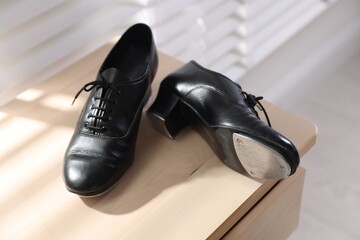 Pair of shoes for tap dance on wooden cabinet indoors, closeup