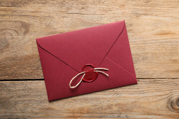 Envelope with wax seal and twine on wooden table, top view