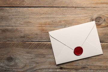 Envelope with wax seal on wooden table, top view. Space for text
