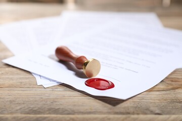 Documents with wax seal and stamp on wooden table, closeup