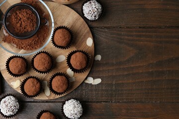 Delicious homemade candies with cocoa powder and coconut flakes on wooden table, flat lay. Space...