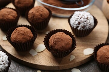 Delicious homemade candies with cocoa powder and coconut flakes on wooden table, closeup