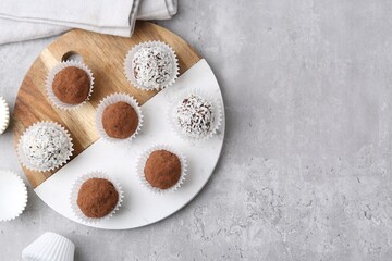 Delicious homemade candies with cocoa powder and coconut flakes on light grey table, flat lay....