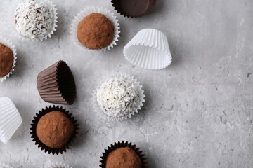 Delicious homemade candies with cocoa powder and coconut flakes on light grey table, flat lay....