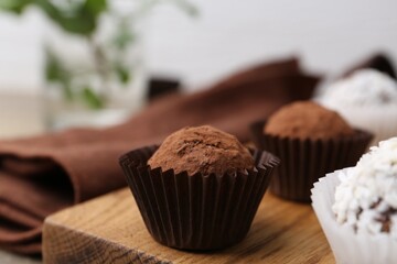 Delicious homemade candies with cocoa powder and coconut flakes on table, closeup