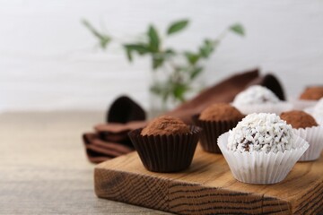 Delicious homemade candies with cocoa powder and coconut flakes on wooden table, closeup. Space for...