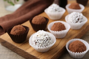 Delicious homemade candies with cocoa powder and coconut flakes on table, closeup