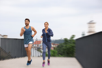 Fototapeta premium Man and woman in sportswear running outdoors, motion blue effect