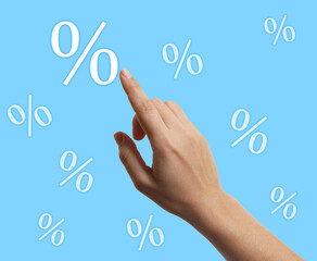 Woman touching virtual percent sign against light blue background, closeup