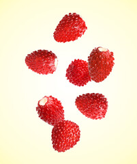 Fresh ripe wild strawberries falling against beige background