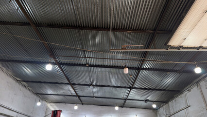 Obraz premium Industrial ceiling with metal roof and lighting fixtures in warehouse or garage space