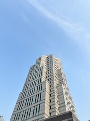 Fototapeta premium Modern High-Rise Office Building with Glass Facade Against Clear Blue Sky 