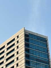 Modern High-Rise Office Building with Glass Facade Against Clear Blue Sky
