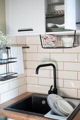 functional and aesthetic kitchen corner with a black sink surrounded by light tiles and a wooden countertop, complemented by practical kitchen accessories and gypsophila decor