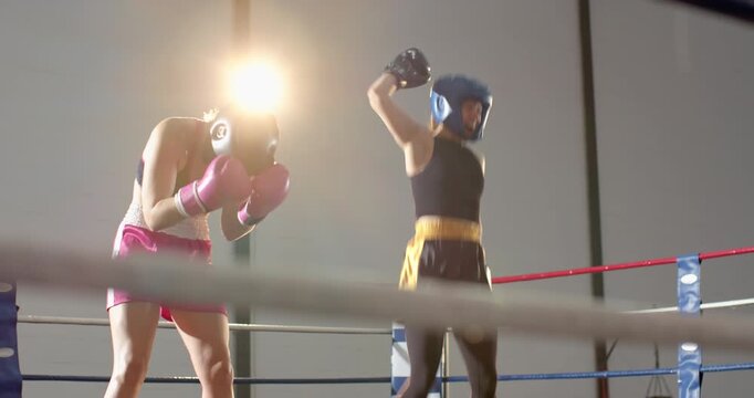 Round ending, female boxer raising gloved hand celebrating win, hugging coach in boxing ring