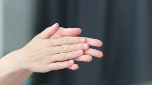 Woman's clapping her hands on gray background and waving saying greeting, goodbye making hand gestures.