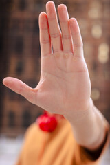 Hand gesture signaling stop or refusal, close-up of extended palm in focus with blurred background,...