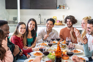Group of multicultural friends enjoying spaghetti and red wine at home. Concept of friendship, Italian cuisine, togetherness and joyful dining in a cozy and welcoming atmosphere.
