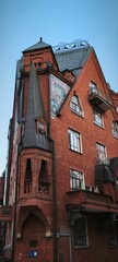 Red brick building with complex architectural details, including towers and intricate window designs. This red brick building features a blend of gothic and modern styles,