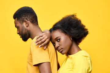 A couple in matching yellow outfits exuding strong emotions against a vibrant yellow backdrop,...