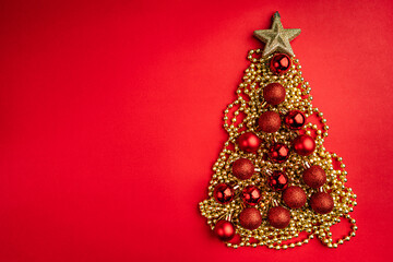 Christmas tree shape made of red and gold ornaments with a glitter star on top, on a red background. Perfect for festive greeting cards, holiday banners, and seasonal promotions.