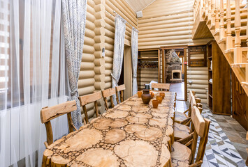 A rustic dining room with a wooden table and chairs. The table is covered with a wooden top and has...