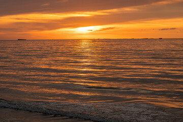 Fototapeta premium Asnelles-Sur-Mer, France - 08 08 2025: Panoramic view of the sea, waves, artificial port and the colorful cloudy sky at sunset along the jetty
