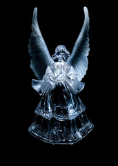 A glass angel figurine with outstretched wings against a black background.