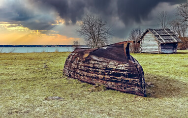 Old fishing boat in the field near a lake in autumn