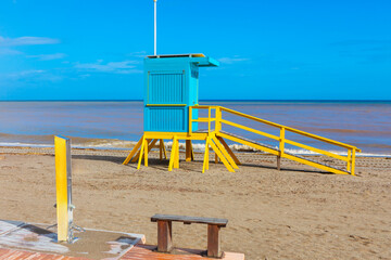 Cheerful lifeguard stand sits on a sunny beach, with gentle waves and clear skies in the...
