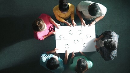 Top down view of business people put last piece of jigsaw puzzle together to complete puzzle and...