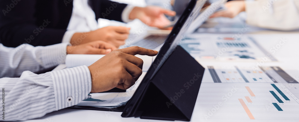 Poster a diverse group of business professionals engaged in a meeting, analyzing data displayed on a tablet