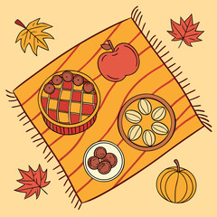 Autumn picnic spread with pie, apple, nuts, and pumpkin on a cozy blanket