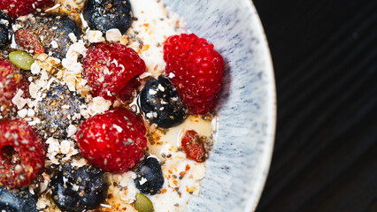 Nutritious yogurt parfait with fresh raspberries, blueberries, oats, chia seeds and honey drizzle. Perfect for healthy food blogs and breakfast photography.