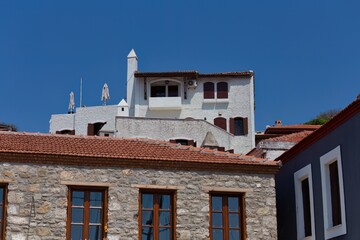 various building styles, including a stone structure with a red tile roof and a white building with dark-framed windows. A clear blue sky is in the background in old Marmaris - Mugla - Turkey