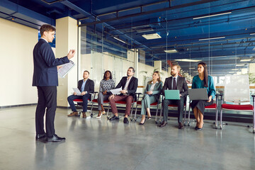 Man speaker talking on a work meeting in modern office in front of a small group of confident...