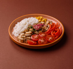 Bowl with chicken pieces, rice, tomatoes, peppers and microgreens. Bowl with chicken