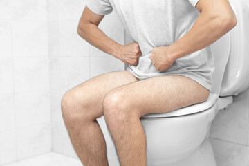 Sitting on toilet with suffering from constipation or hemorrhoid. Feels uncomfortable in his...