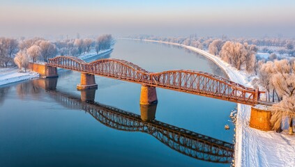 Winter sunrise over a river bridge.  Frozen trees, calm water reflection